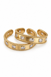 A pair of gold-toned cuff bracelets with clear rectangular gemstones, shown on a plain white background.