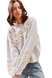 Model in a grey crew neck sweater featuring cream 3D embroidered flowers across the front and sleeves, styled with casual denim jeans.