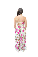 Picture of the back of a spaghetti strap ivory jumpsuit with a pink floral print. Back features an elastic band with a cutout and tie beneath the sqaure cut out 