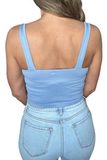 back of the a blue ribbed cami tank top, backline is square with thicker spaghetti style straps. Model is wearing light washed blue jeans