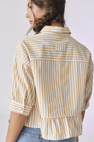 Back of a Woman wearing a white and tan striped collared button down 3/4 sleeve top. Shirt is paired with light denim bottoms