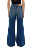 Rear view of a person wearing high-waisted, wide-leg blue denim jeans with a black top, shown against a plain white background.