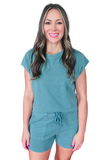 A woman wearing a lightweight teal matching lounge set featuring a relaxed crew neck top and elastic waist shorts with front patch pockets.