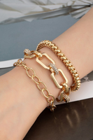 Gold chunky bracelet set on a woman's arm . Set includes three gold bracelets: popcorn style gold elastic bracelet,  a rectangle links with pave rhinestone links, gold oval link chain bracelet 