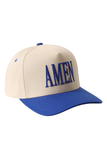 A baseball cap with a cream-colored crown and a royal blue brim, featuring the word 'AMEN' embroidered in blue on the front.