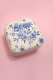 Blue and white floral-patterned jewelry box on a pink background