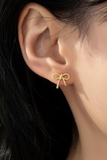 photo of small bow gold stud earrings on a woman's ear