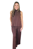 A woman modeling a sleeveless high-neck top and matching wide-leg pants in a solid dark brown color, set against a plain white background.