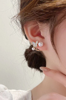 Pearl and butterfly ear jacket on a woman's ear. Butterfly is white and there is gold detailing on the ear jacket