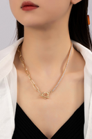 Woman wearing a toggle closure necklace. Necklace is 17 inches long. Half of the necklace is a rhinestone chain, the other whaled are gold oval links. 