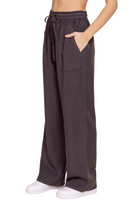 side view of charcoal tencel fabric drawstring pants, hand is resting in the front pocket 