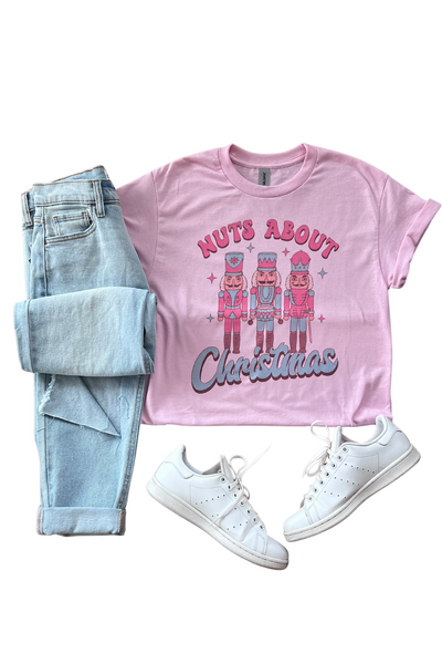 Christmas graphic tee and jeans. T-shirt is light pink with 3 nutcrackers on it and reads "Nuts About Christmas"