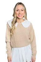 woman wearing a tan cable knit sweater with a white doll collar , sweater is paired with a white pleated skirt 