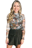 woman wearing a floral long sleeve turtleneck with a olive green corduroy pleated skort 