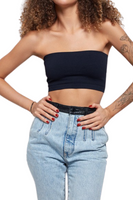 woman wearing a black cropped tube top with denim pants that have a black leather waistband and belt loops 