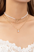 A set of three necklaces featuring a pearl chain choker with a toggle closure, a fine paperclip chain, and a delicate twisted chain with a CZ pendant on neck