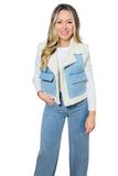 woman wearing a white long sleeve shirt and light denim pants with a white sherpa lined denim vest. The vest has 2 cargo pockets with a flap and button closure. 