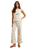 Woman wearing cream mallard print high rise wide leg cropped jeans styled with sleeveless duck graphic sweater and brown sandals.