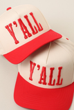 Two cream and red trucker-style caps with red embroidered 'Y'ALL' lettering on the front panels, shown on a light neutral background.