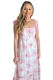 Woman wearing a white and pink floral maxi dress with a square neck line. Dress is an empire waist with crochet detailing along the top and straps. 