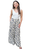 Woman wearing a ivory tank top with floral print wide leg pants. Pants have a navy base with ivory flowers.