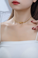 Woman wearing a gold herringbone chain bow necklace
