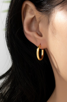 photo of simple gold hoops in a woman's ear. 