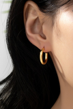 photo of simple gold hoops in a woman's ear. 