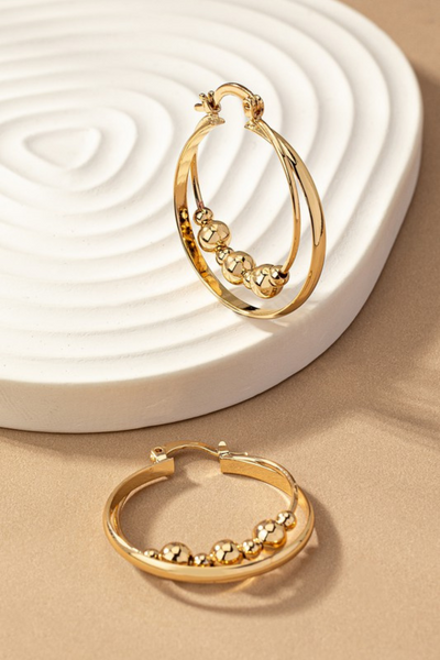 gold layered hoop earrings with circular gold beads on the inner hoop. Hoops have latch closures.