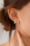 Woman wearing a Gold bow stud earring on her ear lobe