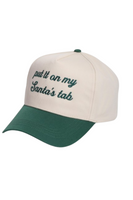 Cream and green Christmas trucker hat with a snapback closure, featuring embroidered green script text on the front that reads, “put it on my Santa’s tab.”