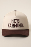 A structured baseball cap with an off-white crown and a dark brown brim, featuring the embroidered text 'HE'S FARMING.' in dark brown on the front.