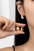 puffy huggie style earrings being held up to an ear for sizing reference 