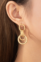 gold intertwined hoop earrings on a woman's ear