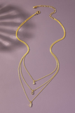 Layered gold chain necklace with 3 delicate chains that have small clear rhinestone charms.