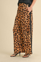 upclose side photo of satin line leopard drawstring leopard pants. Pants have a black stripe running down the side of the leg.