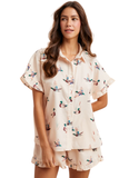 Woman modeling a silky satin feel mallard duck print matching shorts set featuring a button down collared top with ruffle sleeves and relaxed fit drawstring shorts with ruffle hem details.