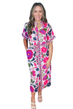 A woman modeling a short-sleeve midi shirt dress with a vibrant, multicolor floral and paisley print on a white background, paired with beige strappy heels against a plain white studio background.