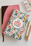 A spiral-bound notebook labeled 'My Bible Study Tracker' with a colorful botanical pattern, styled on a light surface with a pink and brown Bible, pastel sticky notes, and two pens.