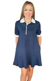 A woman modeling a navy blue short-sleeve dress with a white ruffled collar and white ruffled sleeve cuffs, set against a plain white background.