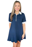 A woman modeling a navy blue short-sleeve polo dress with a white collar and white sleeve cuffs, set against a plain white background.