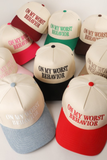 Assorted 2 toned snapback hats with “On My Worst Behavior” embroidered lettering in various color combinations such as cream and red, cream and pink, cream and green, and cream and black.