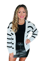 Woman wearing a black and white striped cardigan over a black shirt, styled with a black leather mini skirt 
