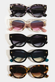 Oversized women's cat eye shape sunglasses. 5 different color options. Colors from top to bottom are: gray tortoise shell, clear with pink sides, black, black with teal sides, brown tortoise shell.