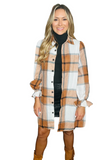 woman wearing a plaid button down shacket over a black turtle neck sweater and black leather skirt. Plaid pattern is composed of white, black, camel and orange colors 