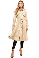 woman wearing a beige pleated trench coat. Coat is called has brown buttons down the front, and has a front waist tie 