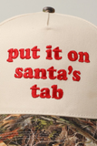 Detailed view of red embroidered “Put It On Santa’s Tab” lettering on tan and camo holiday snapback hat.