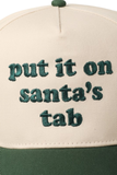 upclose photo of a cream and green trucker hat featuring embroidered green text on the front that reads, “put it on santa’s tab.”