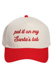 Cream and red Christmas trucker hat with a snapback closure, featuring embroidered red script text on the front that reads, “put it on my Santa’s tab.”