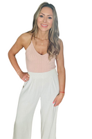 Woman wearing a light pink ribbed sweater cami tank top with ivory linen palazzo pants 